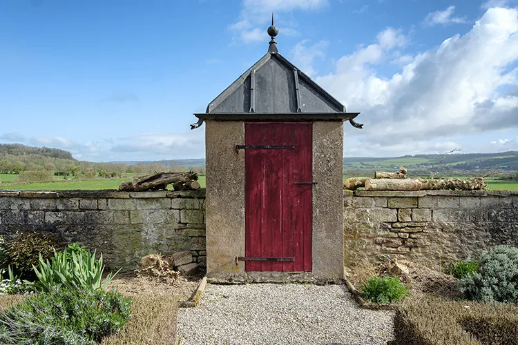Small historic stone building with a red door
